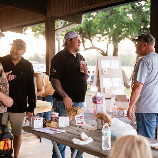 Group_of_men_gathered_at_picnic_tables_talking_at_sscdsg_event