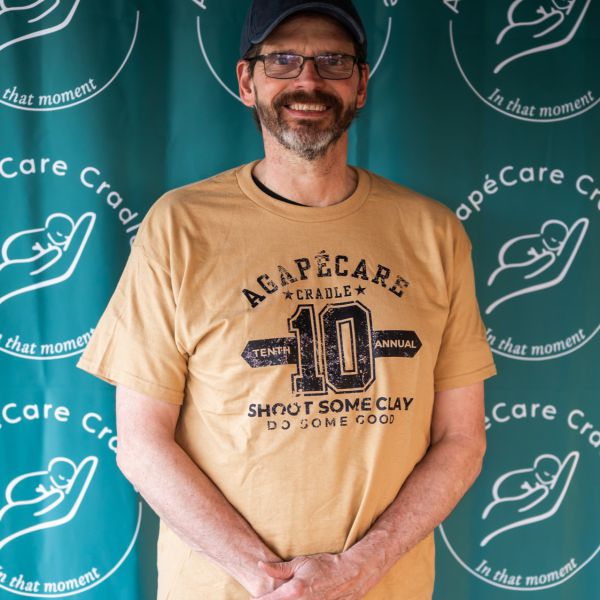 Man_in_yellow_tshirt_posing_with_logo_background