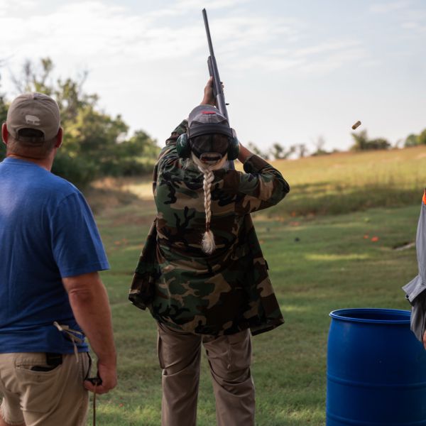 Man_shooting_clay_two_people_watching_one_of_them_shooting_clay_Clear_blue_sky