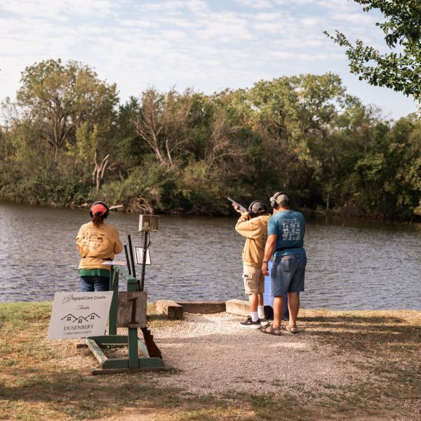 Three_men_clay_shooting_beside_a_river